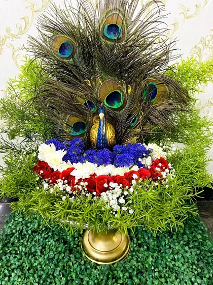 I design unique, thematic trays like this stunning peacock arrangement. A golden peacock figurine is surrounded by peacock feathers, lush greenery, and colorful flowers, creating a vibrant and auspicious centerpiece for any celebration.