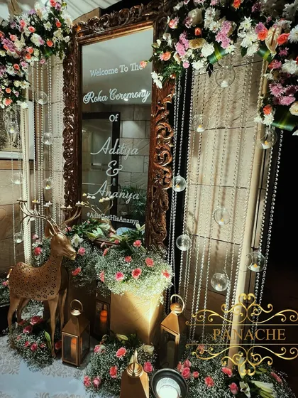 A personalized welcome mirror for the Roka ceremony, framed with lush florals and whimsical elements like a golden deer. This creates a beautiful and personalized photo spot for the couple and guests.
