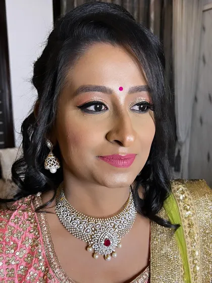 A side profile of this glittery reception makeup. The light catches the shimmer on her eyelids beautifully, and the bright pink lip adds a youthful and festive touch to her overall look.