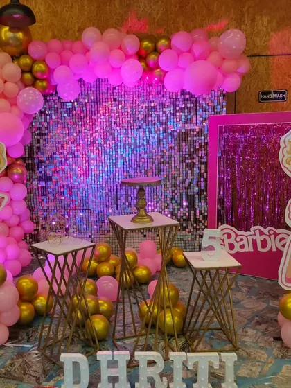 A glamorous Barbie party with a pink sequin wall and multiple character cutouts. The gold and pink balloon arch adds to the sparkle.