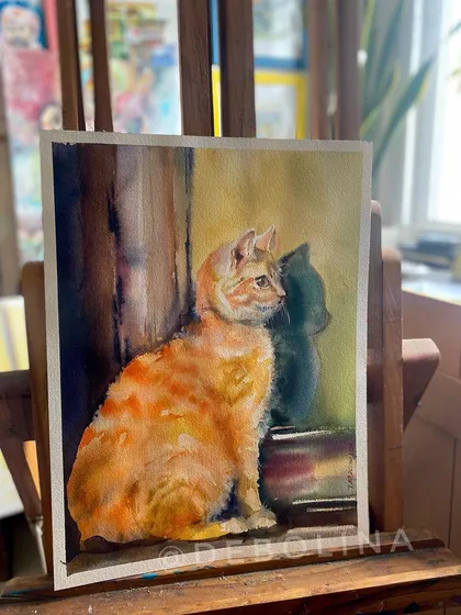 The finished cat painting displayed on my easel. The warm sunlight from the window adds a lovely glow to the scene, highlighting the cat's soft fur.