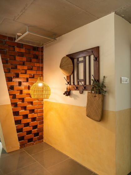 An interior view of the living space, defined by an inclined wall and a mix of natural materials. The half-height wall is finished in yellow oxide, contrasting with the exposed brick and creating a warm, inviting entryway.