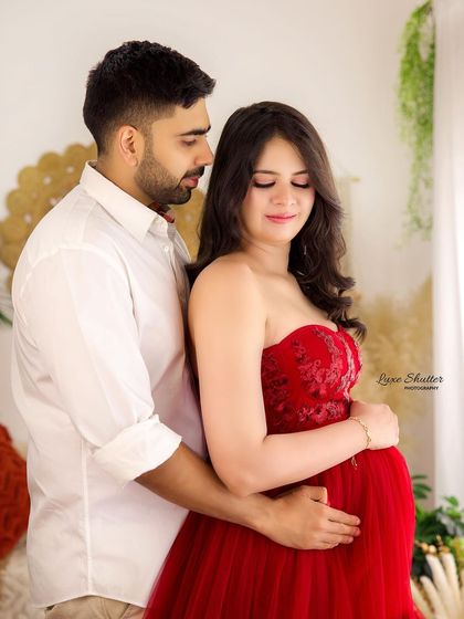 This close-up shot focuses on the pregnancy glow and the tender embrace of the couple. The red gown and boho backdrop add warmth and elegance to this maternity photo.