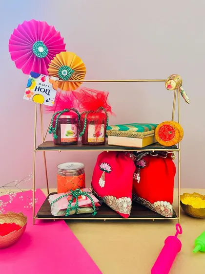 A two-tiered stand makes for a grand Holi gift. I've arranged jars of treats, colorful potlis, and other festive items on it, creating an impressive and generous hamper.