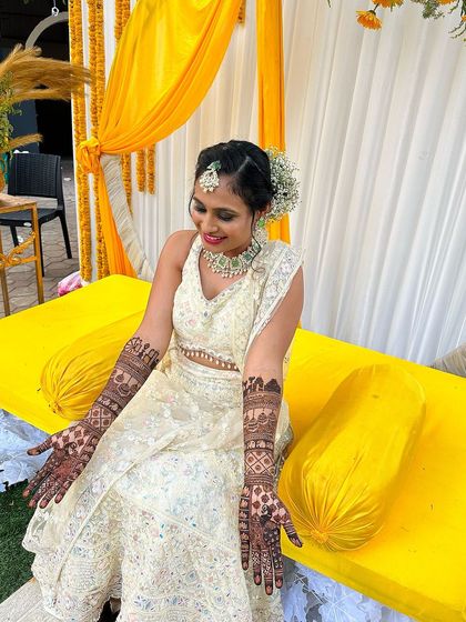 A bride looking lovely in her yellow and white outfit for her mehndi ceremony.