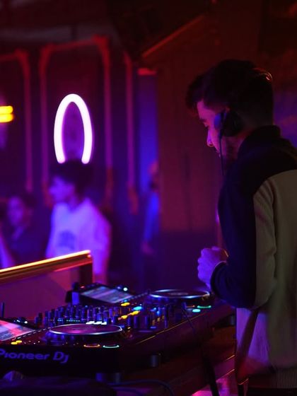 A side view of me at the Pioneer DJ console at H.O.D, surrounded by the club's unique neon decor. I focus on every detail to build the perfect set for the room.