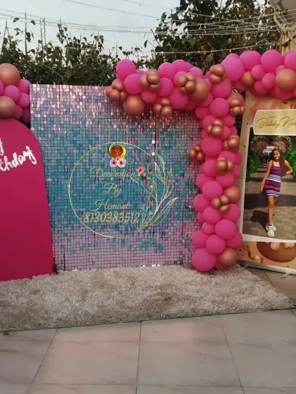 A glamorous birthday photo booth with a pink sequin wall that shimmers in the light. The setup is completed with a pink balloon arch, a custom "Happy Birthday" sign, and a personalized photo standee.