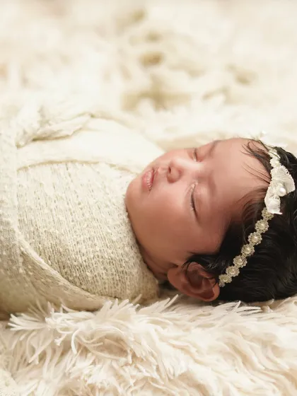 A side profile of the swaddled newborn, showcasing her delicate features and the soft lace headband. This angle provides a different, equally beautiful perspective.