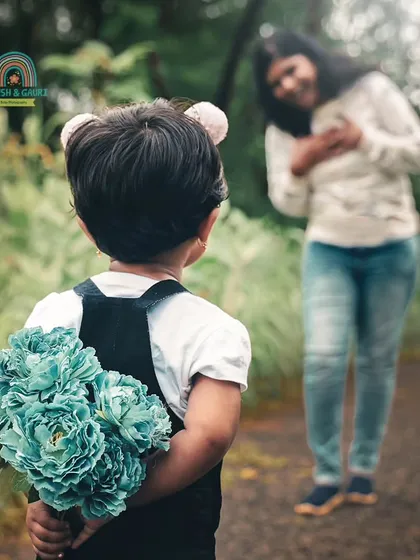 A surprise for mom. This heartwarming shot captures a sweet moment of a child about to give flowers to her mother during their family photoshoot.