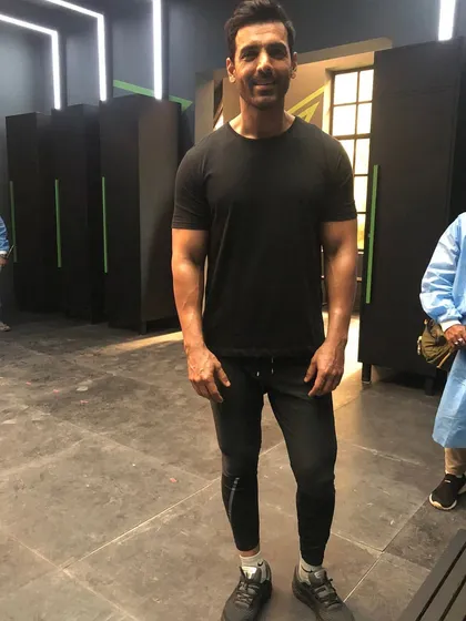 John Abraham on set in a simple, athletic look. Even in a basic black t-shirt and joggers, the right fit is key to looking sharp.