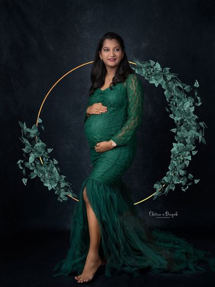 Modern elegance. The clean lines of the golden ring prop contrast beautifully with the delicate lace of the green gown, creating a sophisticated maternity portrait.