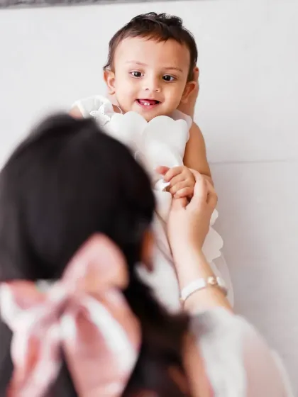 An over-the-shoulder view showing the baby's sweet expression as she looks at her mother. A creative angle for a touching family moment.