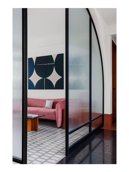 A view into the family lounge through an arched metal and glass screen. This image showcases my focus on materiality, with terrazzo floors, granite infills, and a continuous terracotta-hued skirting.