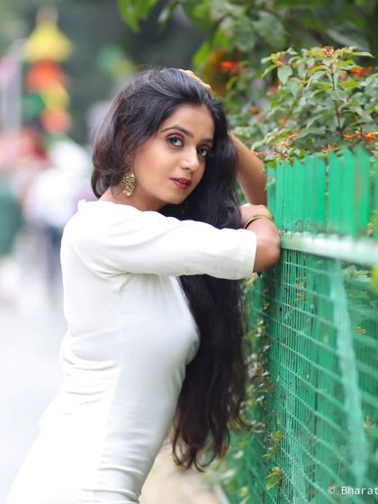 A candid-style portrait taken on the street. The green fence provides a nice color contrast for this outdoor shot.