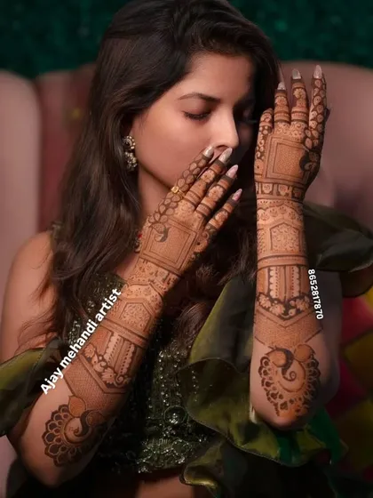 An elegant pose from a client showing her beautiful mehndi, which features peacock motifs and geometric patterns.