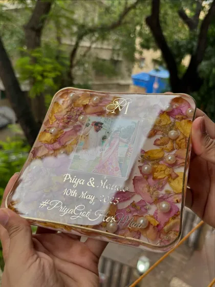 A close-up of a 6x6 inch square keepsake. You can see how the pink and yellow petals are layered with pearls, creating depth and texture around the couple's photo and monogram.