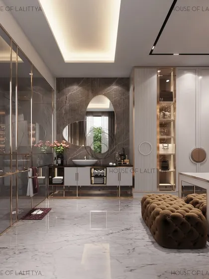We designed this washroom and walk-in closet to be both stylish and functional. The space features an asymmetrical mirror, a fluted vanity with gold accents, and a central island with a tufted ottoman for a luxurious dressing experience.