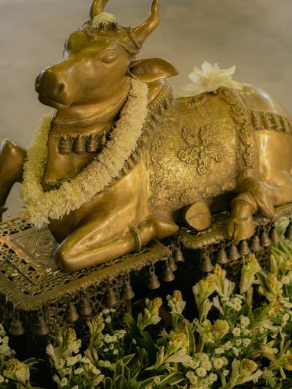 We incorporate sacred symbols to add depth and meaning to the decor. This brass Nandi, adorned with a simple floral garland, was placed at the entrance to bless the couple's union with strength and purity.