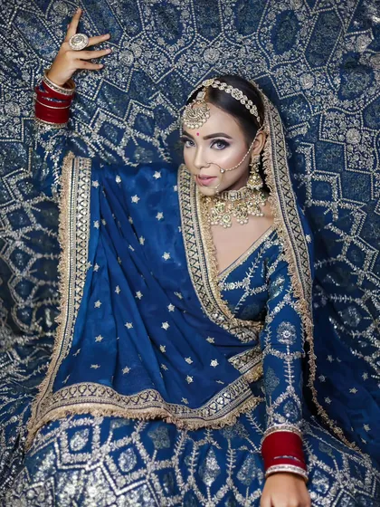A full-length shot of the bride in her magnificent blue lehenga. This demonstrates the ability to create a cohesive look that ties together the outfit, jewelry, hair, and makeup.