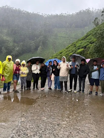 A group with umbrellas and raincoats, fully embracing the rainy weather in Munnar. The monsoon season brings out the best in these green landscapes.