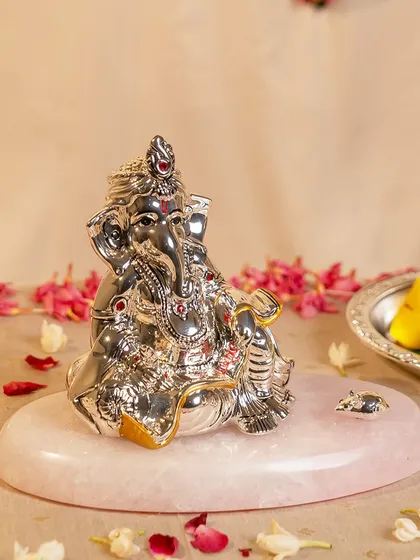 This silver-plated Ganesha idol, placed on a smooth rose quartz slab, is a beautiful centerpiece for Ganeshotsav celebrations. The contrast of cool silver and warm pink stone is both modern and timeless.