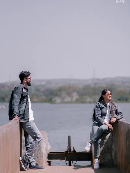 A relaxed, candid-style photo of the couple by the water. Their casual denim outfits are perfect for this natural, serene location.