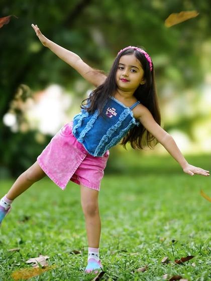 A carefree moment in the park, with a young girl playing among falling leaves. These candid shots are full of life and movement.