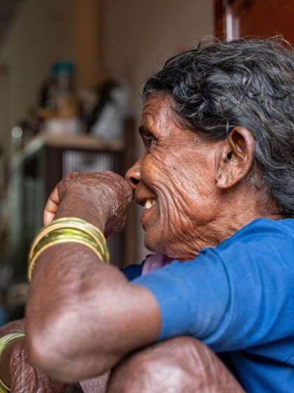 A candid, side-profile shot of the 'aaji'. This black and white photo focuses on the beautiful textures of her wrinkled skin and her gentle smile, telling a story of a life fully lived.