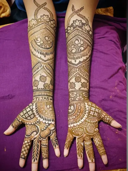A perfectly symmetrical, full-coverage bridal mehandi that extends up to the elbows. This design features the groom's name, 'Tejas', hidden on the palm, surrounded by traditional Indian henna patterns.