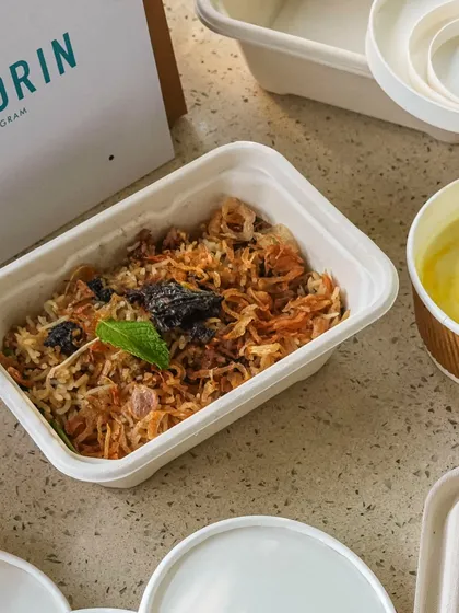 Our celebrated Gucchi Pulao, packed for delivery. The fragrant rice and morel mushrooms are carefully placed in our eco-friendly containers, ready to be paired with the accompanying raita.