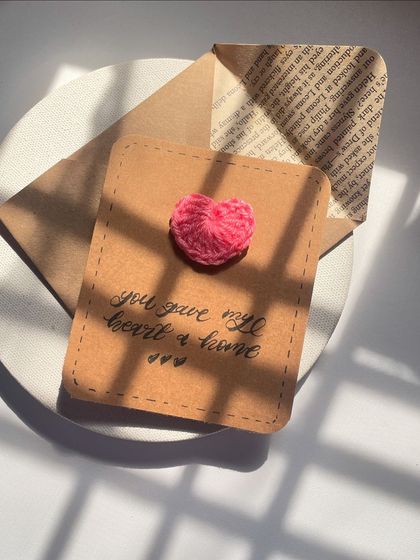 The lighting in this shot is just perfect! It really highlights the handmade quality of the crochet heart card and its simple, sweet message.
