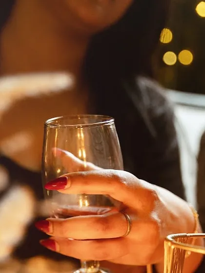 A guest holds a glass of wine, with the soft bokeh of fairy lights in the background. It's these small, beautiful moments that define an evening at Shamiyana.