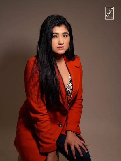 A strong and confident portrait of a model in a bold red blazer, looking directly at the camera.