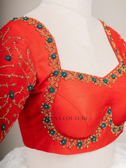 A simple yet striking design. This bright red raw silk blouse features a delicate creeper embroidery pattern in gold and teal thread, with a classic square back and matching handmade tassels.