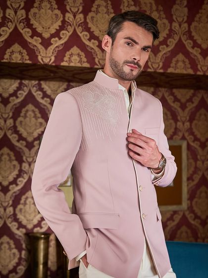 I love working with pastels. This baby pink Jodhpuri suit features delicate ivory thread embroidery on the shoulder, offering a soft yet masculine look for a destination wedding.