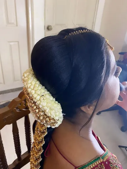 A close-up side view of the hair bun portion of a traditional bridal braid. The neat puff and the placement of the jasmine and gold accessories are key to achieving this polished look.