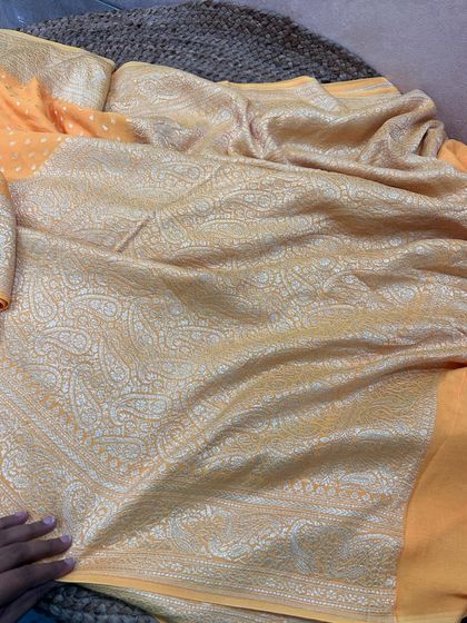 The complete look of this mango yellow Banarasi silk saree. The pallu is adorned with a beautiful paisley jaal in silver zari.