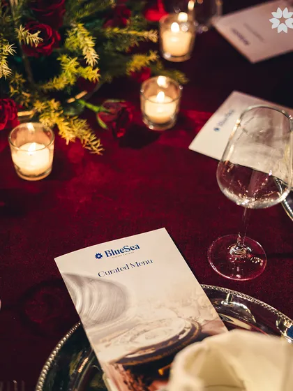 A personalised table setting at our Worli venue. The deep red tablecloth and warm candlelight create an intimate and romantic atmosphere, perfect for a wedding reception or anniversary dinner.