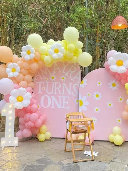 A different perspective of the daisy flower theme, showing the light-up marquee number '1' and the full arrangement of the pastel balloon arches against a natural bamboo background.