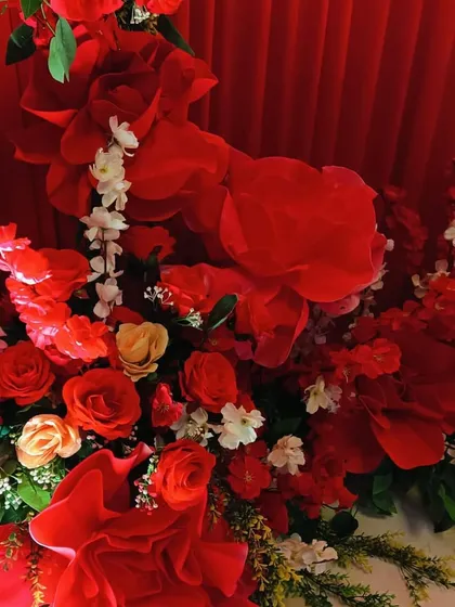 A close-up of the lush red floral arrangements, showing the mix of large paper flowers and fresh roses used to create a rich, textured look.