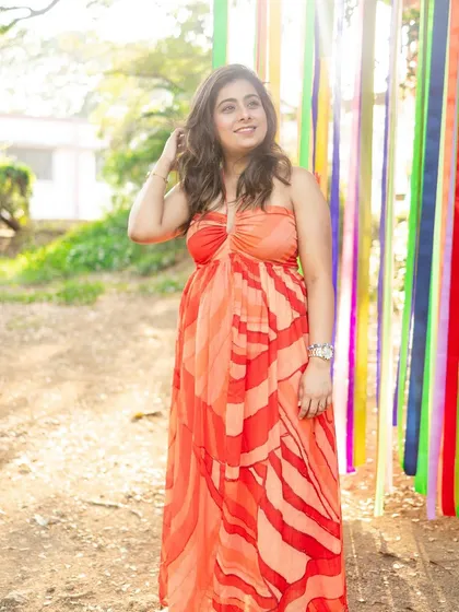 The bride-to-be in a vibrant orange dress. The soft, natural makeup ensures the focus remains on her and the beautiful colors of her outfit and the surroundings.