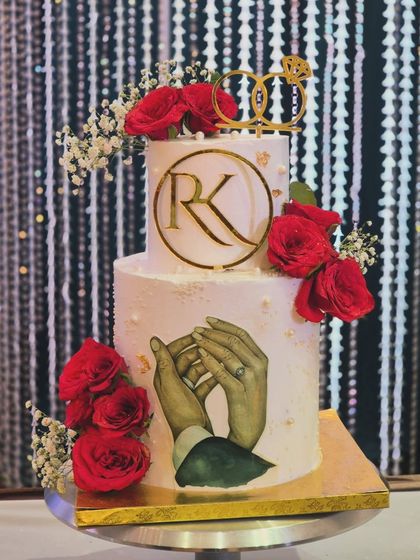 Another angle of the 'RK' engagement cake, showing how the fresh flowers and gold accents come together against the clean white frosting.