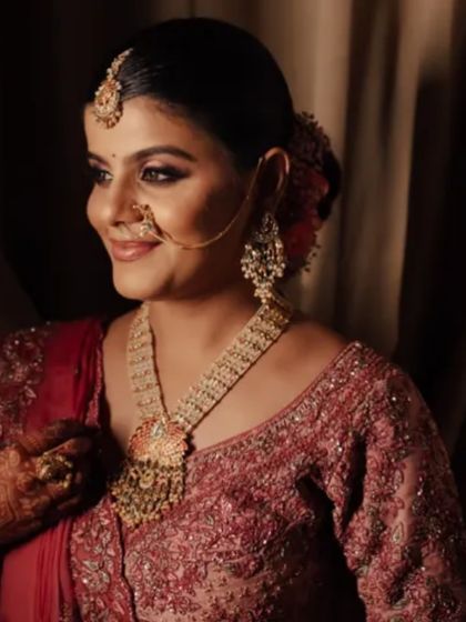 A side profile of the bride, showcasing her elegant bun adorned with flowers and her stunning temple jewelry. The makeup is kept classic to balance the ornate details.