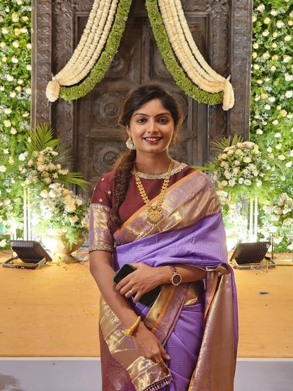 The same client in her purple saree and brocade blouse, now facing forward with a lovely smile.