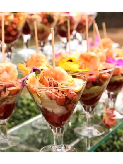 A sophisticated seafood cocktail served in a martini glass, featuring prawns, noodles, and fresh vegetables. This is a visually stunning appetizer for a luxury event.