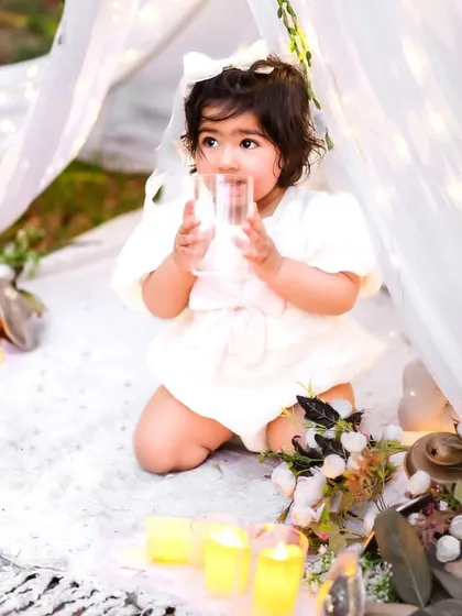 Taking a pretend sip from a glass. These playful, imaginative moments make for wonderfully unique first birthday photos.