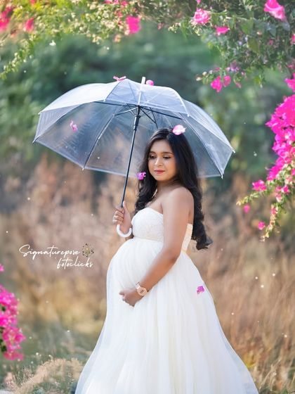 A whimsical outdoor portrait with a clear umbrella amidst falling petals, creating a dreamy and romantic scene.