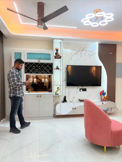This is the 'sukoon' we bring to your home. A look at a completed living and dining area, featuring a custom TV unit with a marble finish back panel and an integrated bar cabinet with dedicated storage for wine bottles and glasses.