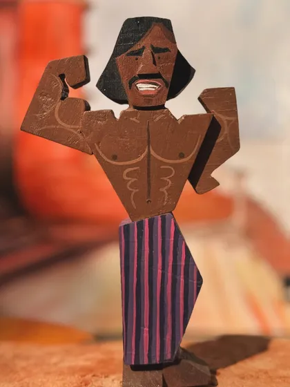 The mighty bodybuilder from the film, brought to life in wood. This figurine captures his impressive physique and flexing pose, adding a memorable character to the collectible set.