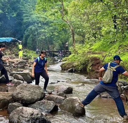 Our guide helping a trekker cross a stream on the way to Devkund. We always ensure our groups move safely.